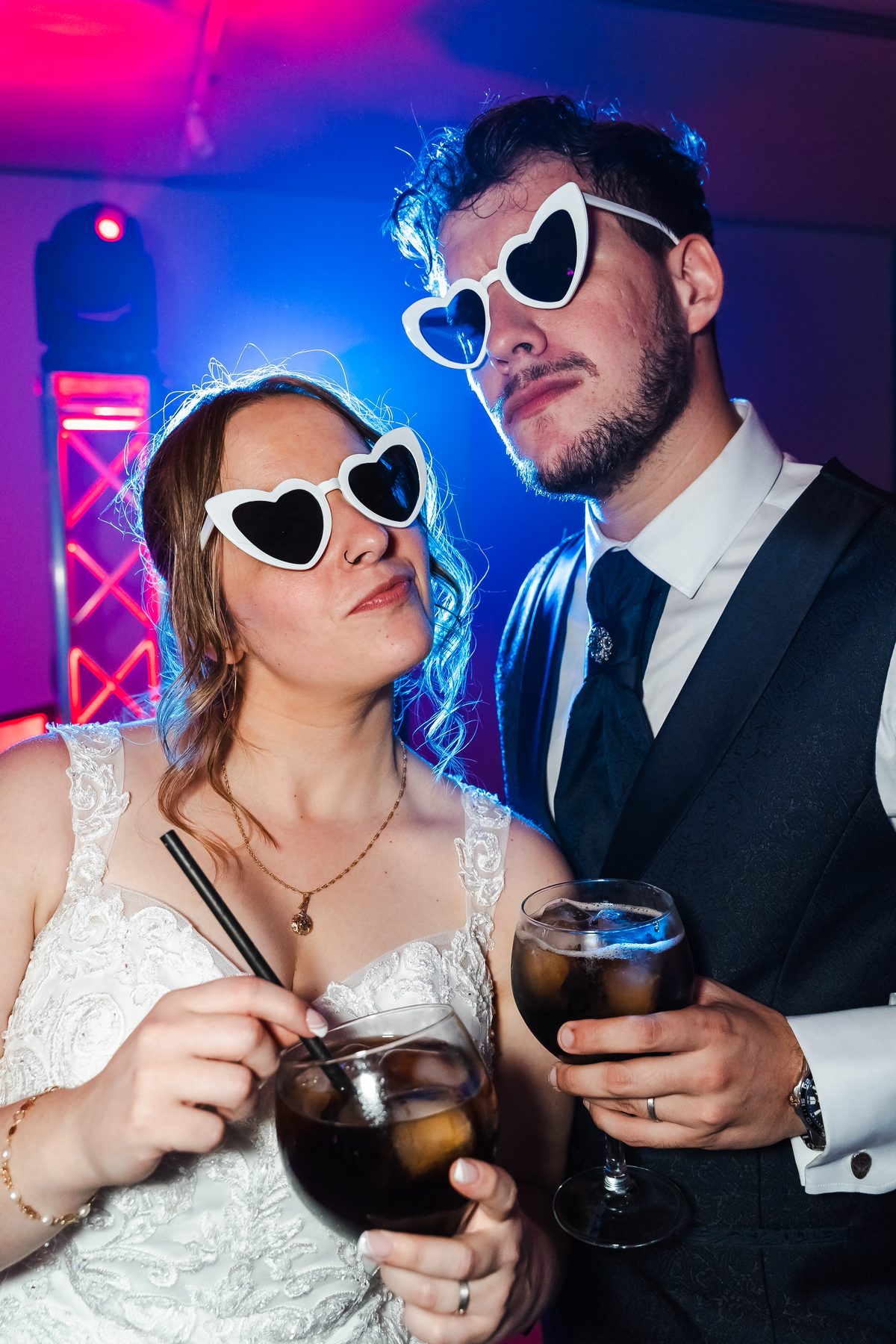 Novios con gafas de corazón y copas en la fiesta